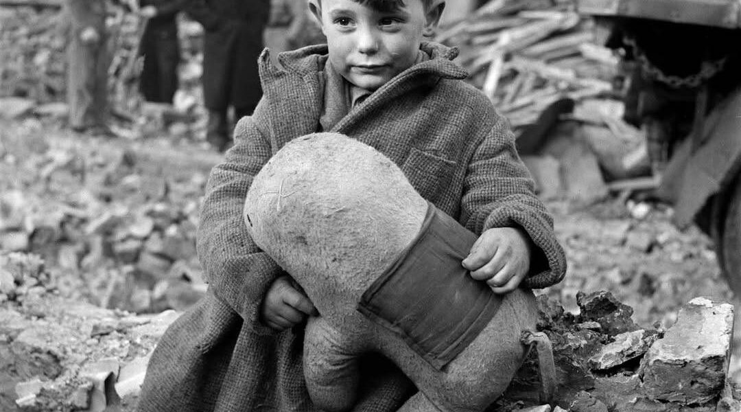 Verlassener Junge hält ein Stofftier inmitten von Ruinen nach deutschen Luftangriffen auf London, 1945