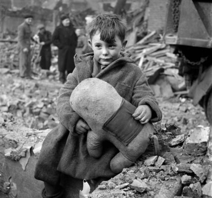 Verlassener Junge hält ein Stofftier inmitten von Ruinen nach deutschen Luftangriffen auf London, 1945