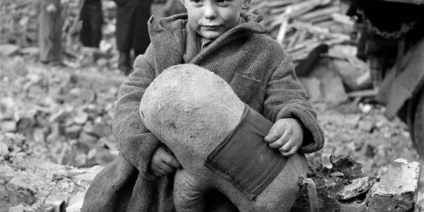 Verlassener Junge hält ein Stofftier inmitten von Ruinen nach deutschen Luftangriffen auf London, 1945