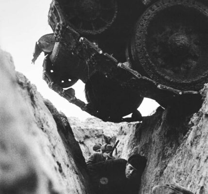 Soldaten der Roten Armee in einem Schützengraben, als ein sowjetischer T-34-Panzer über sie hinwegfährt, 1943