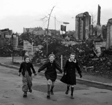 Drei Schülerinnen laufen auf Schlittschuhen von der Schule nach Hause und kommen dabei an zerstörten Häuserblocks in Essen vorbei, 1949