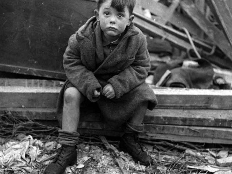 Verlassener Junge hält ein Stofftier inmitten von Ruinen nach deutschen Luftangriffen auf London, 1945