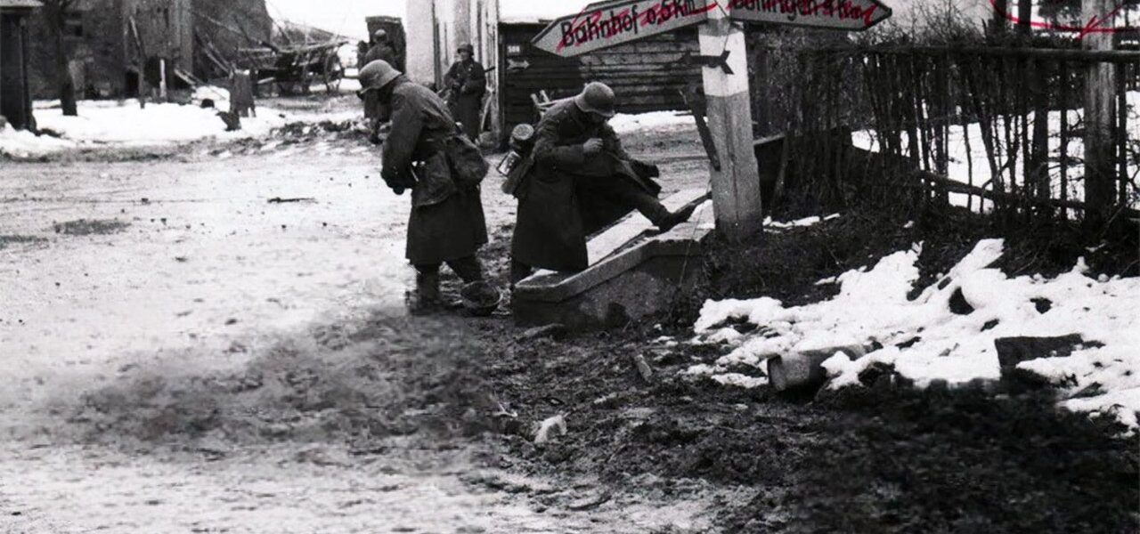 Deutsche Soldaten nehmen toten amerikanischen Soldaten an einer Kreuzung in Belgien Stiefel und andere Ausrustung ab, 1944