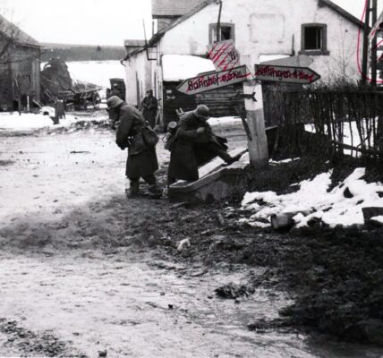 Deutsche Soldaten nehmen toten amerikanischen Soldaten an einer Kreuzung in Belgien Stiefel und andere Ausrustung ab, 1944