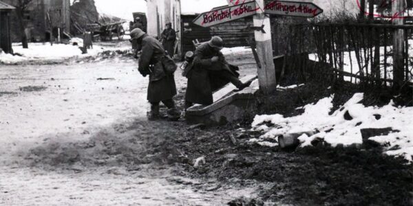 Deutsche Soldaten nehmen toten amerikanischen Soldaten an einer Kreuzung in Belgien Stiefel und andere Ausrustung ab, 1944