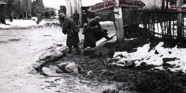 Deutsche Soldaten nehmen toten amerikanischen Soldaten an einer Kreuzung in Belgien Stiefel und andere Ausrustung ab, 1944