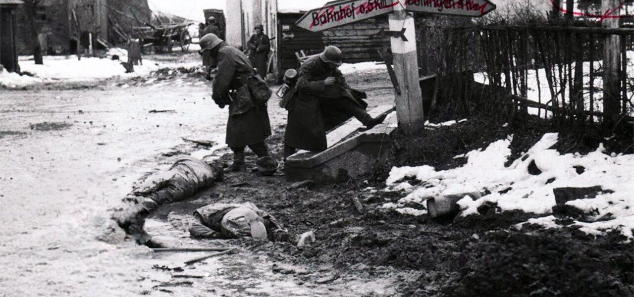 Deutsche Soldaten nehmen toten amerikanischen Soldaten an einer Kreuzung in Belgien Stiefel und andere Ausrustung ab, 1944